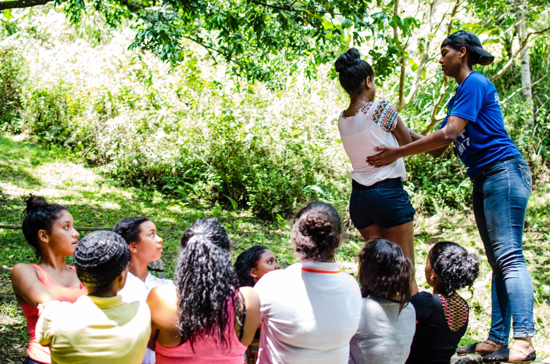 Diverse group participating in an outdoor team building exercise in a lush green setting.