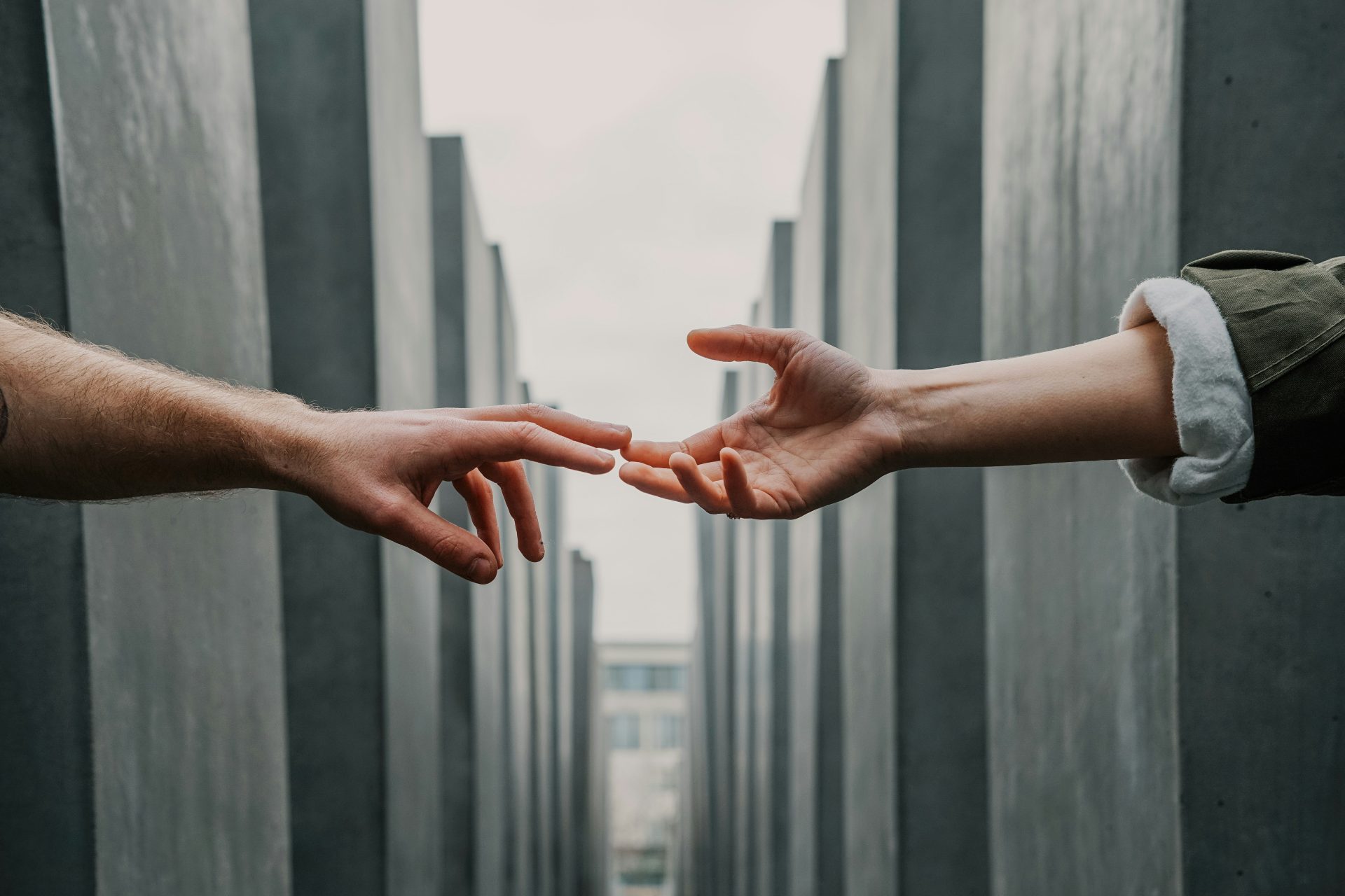 two hands reaching between concrete pillars